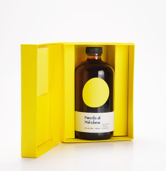 Caja especial para regalo del licor Pastis de México. La caja es color amarillo además contiene un cuadernillo con todas las propiedades de las plantas del pastis: anís estrella, anís verde, hinojo, toronjil, orégano, semilla de cilantro, baya de enebro, clavo, jamaica y cempasúchil.